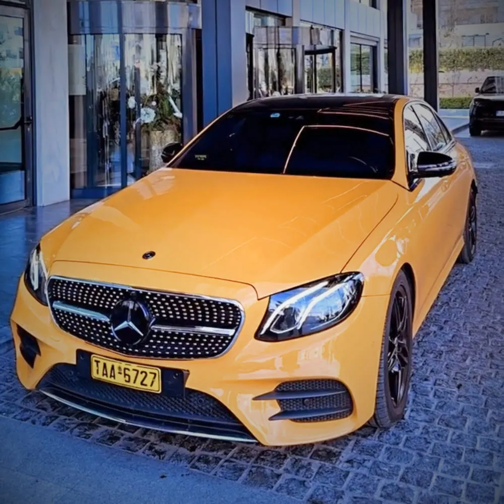 Yellow Mercedes taxi parked outside a glass building entrance